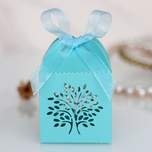 Macro detail of laser-cut Tree of Life design on light blue candy box with ribbon