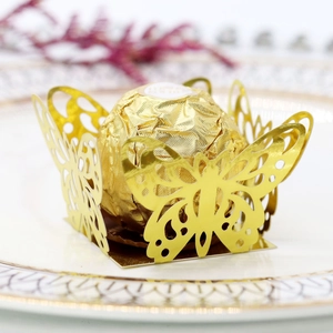 Macro view of laser-cut butterfly cupcake wrapper in gold finish with intricate hollow pattern