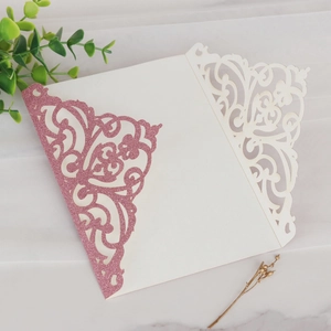 Vue macro d'une invitation de mariage découpée au laser avec paillettes roses et bord dentelle
