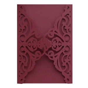 Close-up of laser-cut burgundy invitation cover with intricate floral vine patterns