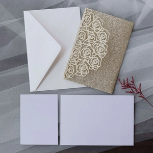 Detail of glitter gold laser-cut rose invitation card with white envelope and inserts