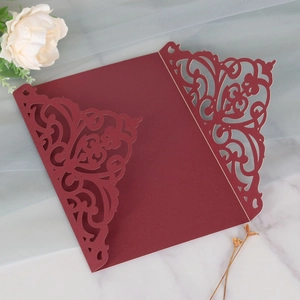 Close-up of laser-cut floral pattern on elegant burgundy wedding invitation cover