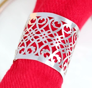 Macro shot of silver metal napkin ring with hollow geometric pattern on red fabric