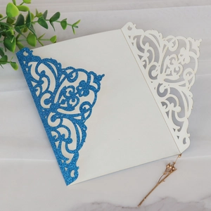 Détail macro du motif floral découpé au laser et paillettes bleues sur faire-part chic