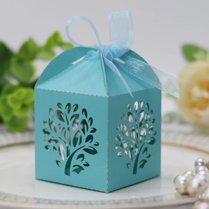 Close-up of light blue laser-cut candy box with tree pattern and organza ribbon