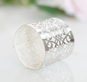 Detail of silver hollowed lace napkin ring with intricate laser-cut floral patterns