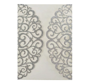 Detail view of silver glitter laser-cut wedding invitation with elegant scroll patterns