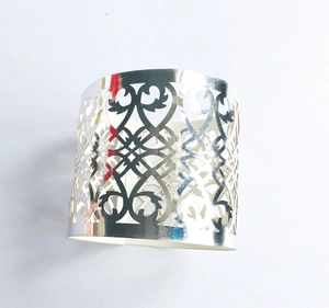 Macro detail of silver metal napkin ring featuring elegant hollow floral cutout patterns