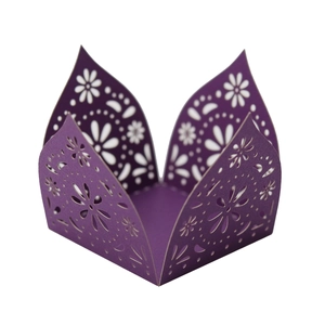 Macro detail of laser-cut purple cupcake wrapper with intricate floral and dot patterns