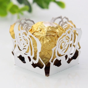 Détail d'une boîte à bonbons blanche découpée au laser avec motifs de roses et un chocolat