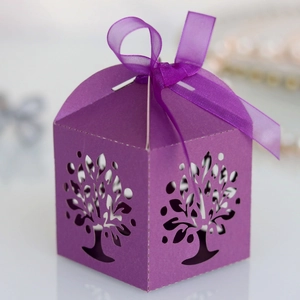 Detail of laser-cut tree of life design on purple wedding candy gift box with silk bow