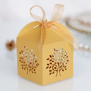 Close-up of golden laser-cut Tree of Life candy box with a shiny orange ribbon bow