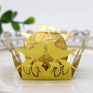Macro shot of gold hollow-out laser cut bird design candy box on a white plate