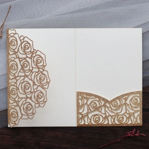 Detail of laser-cut cream wedding invitation with gold glitter rose patterns