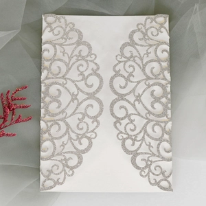 Detail of laser-cut wedding invitation with silver glitter and elegant scroll patterns