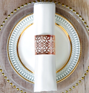 Macro shot of rose gold napkin ring with geometric hollow pattern on a white napkin
