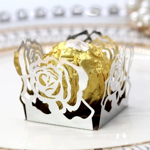 Gros plan d'une boîte à bonbons rose argentée ajourée avec chocolat doré à l'intérieur