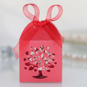 Close-up of red laser-cut Tree of Life candy box with elegant ribbon and pearlescent paper