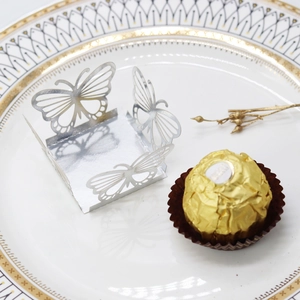 Detailed laser-cut silver butterfly truffle holder on an elegant gold-rimmed white plate