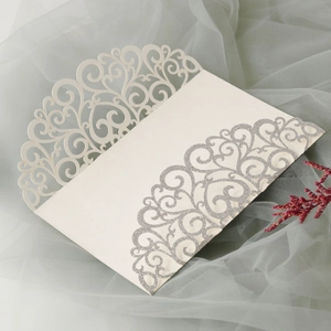 Detail of laser-cut swirl pattern and silver glitter on cream wedding invitation