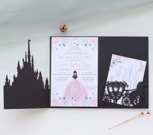 Macro detail of laser-cut black castle invitation with Quinceañera carriage design