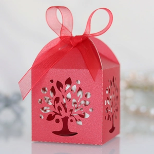 Detail of red laser-cut favor box with tree pattern and a matching sheer organza ribbon