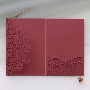 Detail of laser-cut burgundy rose wedding invitation with elegant hollow-out texture