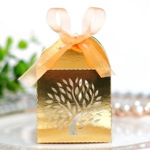 Detail of laser-cut golden candy box featuring life tree pattern and orange silk ribbon