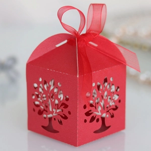 Detail showing laser-cut Tree of Life pattern on red paper candy box with ribbon