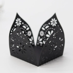Intricate laser-cut black paper cupcake wrapper with floral hollow patterns for weddings