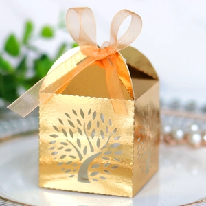 Close-up of golden hollow Tree of Life candy box with orange ribbon and laser-cut details