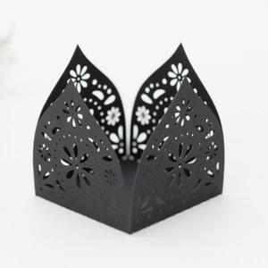 Macro detail of laser-cut black cardstock cupcake wrapper with floral hollow patterns