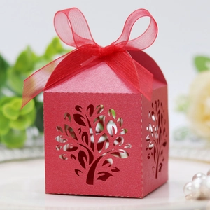 Detailed laser-cut tree design on a red pearlescent cardstock wedding favor box with ribbon