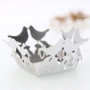 Intricate laser-cut cupcake wrapper with bird and musical note patterns for weddings