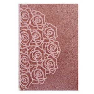 Macro view of rose gold glitter laser-cut rose floral invitation cover with metallic finish