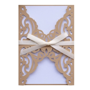 Detail of laser-cut lace champagne gold invitation with a white satin ribbon bow