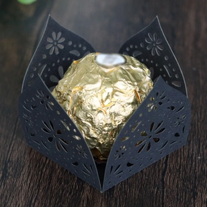 Macro view of laser-cut black paper candy cup with gold foil chocolate on wood background