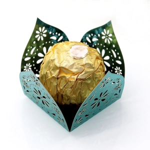 Detail of laser-cut teal cardstock candy box with floral patterns and a gold chocolate