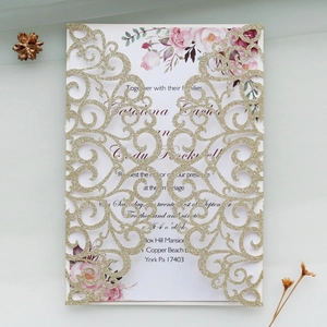 Detail of laser-cut gold glitter wedding invitation with elegant red floral inner card
