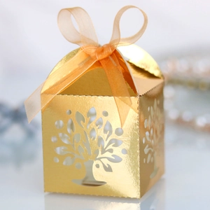 Detail of laser-cut Tree of Life candy box with elegant gold finish and orange ribbon