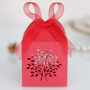 Detail of red hollow tree laser cut favor box with elegant organza ribbon tie