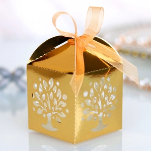 Detail of laser-cut golden tree gift box with elegant orange organza ribbon bow