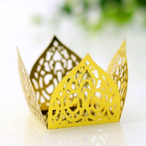 Macro shot of gold laser-cut lace cupcake wrapper with crown-shaped vine pattern