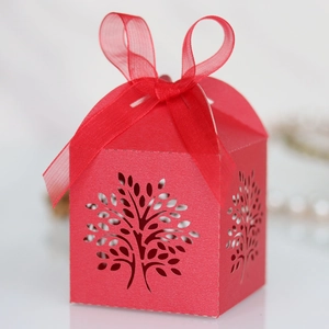 Detailed laser cut tree pattern on red gift box with elegant organza ribbon bow