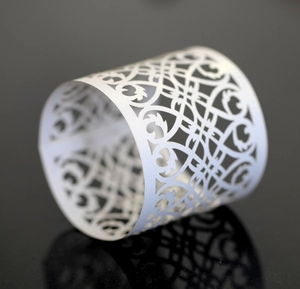 Macro shot of white laser-cut lace napkin ring with intricate pattern on black surface