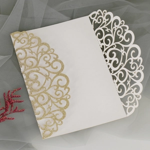 Macro shot of laser-cut wedding invitation with gold glitter European scroll pattern