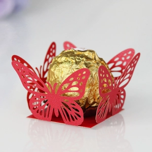 Macro view of red laser-cut butterfly lace candy box with gold chocolate inside