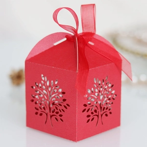 Close-up of laser-cut Tree of Life pattern on red wedding candy box with ribbon handle