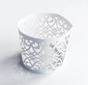 Detailed laser-cut heart and vine patterns on white paper cupcake wrappers for decoration