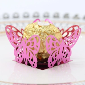 Close-up of pink laser-cut butterfly candy box with detailed lace patterns and chocolate